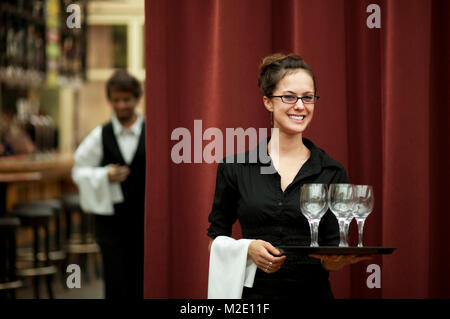 Smiling Hispanic Kellnerin Durchführung fach der Weingläser Stockfoto