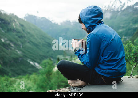 Kaukasische Mann sitzt in der Bergwelt Kaffee trinken Stockfoto
