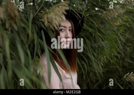 Portrait von schweren asiatischen Frau, die in den Bereich der hohen Gras Stockfoto