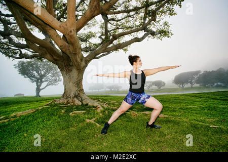 Gemischte Rasse Frau trainieren und sich in der Nähe von Tree Stockfoto