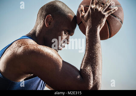 Portrait von Schwitzen Schwarzer Mann berühren Stirn mit Basketball Stockfoto