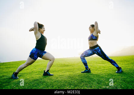 Gemischten rennen Frauen stretching Waffen im Feld Stockfoto