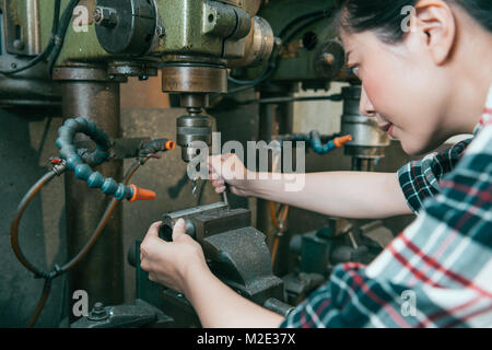 Selektiver Fokus Foto von lächelnden hübsche Frau Arbeiter bohren Teile in Fabrik für Fräsmaschinen. Stockfoto