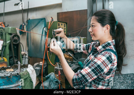 Lächelnd elegante weibliche Arbeitnehmer Personal mit einer Schieblehre Skala Device Tool Verarbeitung Komponenten bestätigen in Fabrik für Fräsmaschinen. Stockfoto