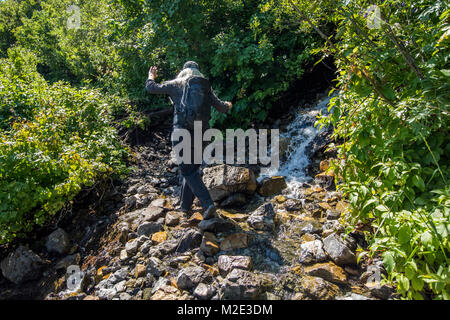 Kaukasische Frau Wandern auf den Felsen im Fluss Stockfoto