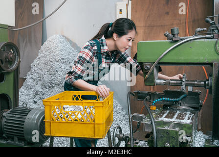 Elegante professionelle Fräsen Arbeiterin an der Maschine und Verarbeitung Teile aus Stahl Komponenten suchen, wenn Sie in der Drehbank Fabrik. Stockfoto