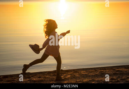 Kaukasische Frau laufen am Strand Holding hat Stockfoto