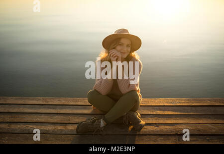 Lächelnd kaukasische Frau sitzt auf der Anklagebank der See Stockfoto