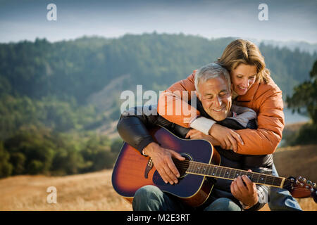 Frau umarmt man Gitarre spielen Stockfoto