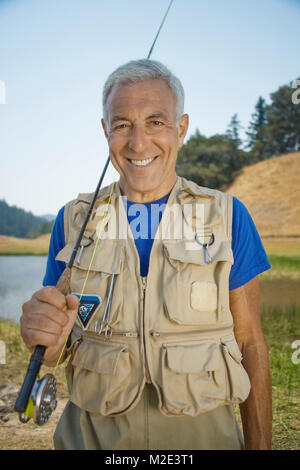 Portrait von lächelnden kaukasischen Mann mit Angelrute Stockfoto