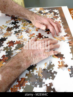 Eine ältere, oder älteren Menschen mit Demenz arbeitet ein Puzzle seine geistigen Fähigkeiten zu schärfen. Oklahoma, USA. Stockfoto