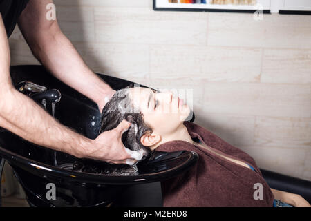 Schöne Mädchen wäscht ihr Haar vor einen Haarschnitt in einem Schönheitssalon. Haare waschen bei einem Friseur, jungen kaukasischen Mädchen. professional Shampoo Friseur friseur Mann Stockfoto