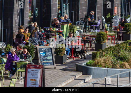 Die Menschen saßen draußen Visto Lounge Cafe auf der Strandpromenade von Torquay in der Sonne im Februar 2018. Sonnigen morgen bei Torquay, Torbay, Devon, Großbritannien. Februar 2018. Stockfoto