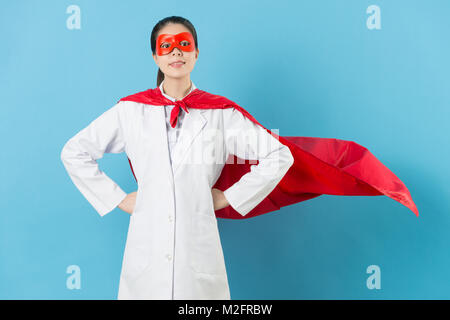 Professionelle Schönheit Frau Doktor tragen Superheld Kostüm mit Maske in Blau unterlegt ist. Stockfoto