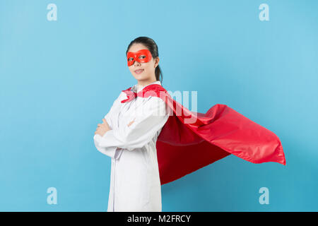 Junge schöne Frau Krankenhaus Arzt Hände gekreuzt an Kamera und das Tragen von Superhelden Kleidung auf blauem Hintergrund isoliert. Stockfoto