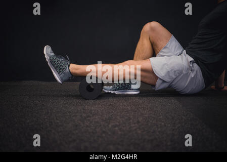 Athletischer Mann mit einer schaumstoffrolle Muskelkater nach dem Training zu entlasten. Stockfoto