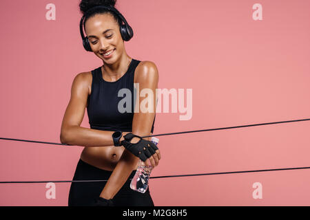 Lächelnde Frau mit Kopfhörern und Wasserflasche Ausruhen nach Training. Passform weiblichen Athleten eine Pause nach dem Training. Stockfoto