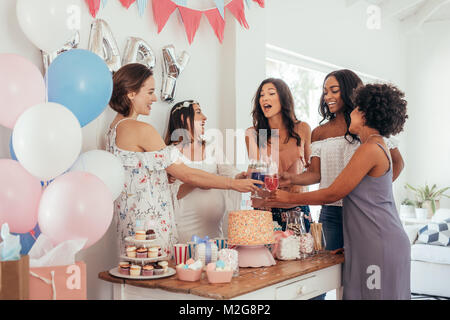 Frauen Toasten mit Säften an Babyduschepartei. Gruppe von Freunden bei Baby Shower party Säfte haben. Stockfoto