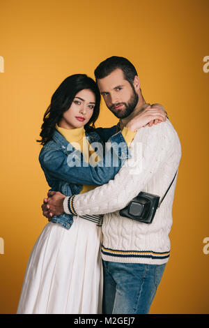 Freund und Freundin umarmen und mit Blick auf die Kamera isoliert auf Gelb Stockfoto