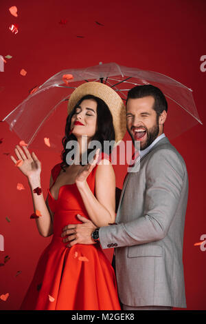 Lachend ein Paar mit Dach, unter fallenden Konfetti rot, isoliert Stockfoto