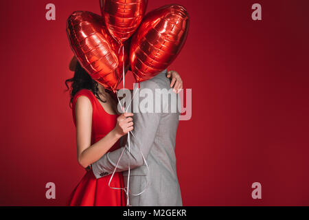Paare, die Gesichter mit Bündel von Ballons rot, isoliert Stockfoto