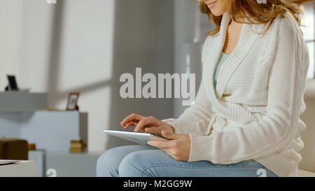 Lächelnde Frau mit App auf Tablet-PC zu Hause, Chatten im Internet, das Anschauen von Filmen in HD Stockfoto