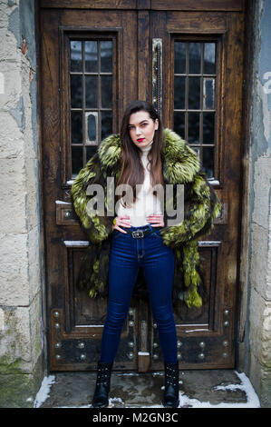 Brunette Mädchen in grün Pelzmantel gegen alte Holztüren. Stockfoto