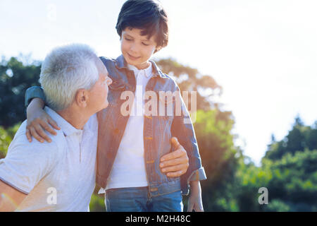 Cute Jugendliche Junge im Gespräch mit liebevoller Großvater im Freien Stockfoto