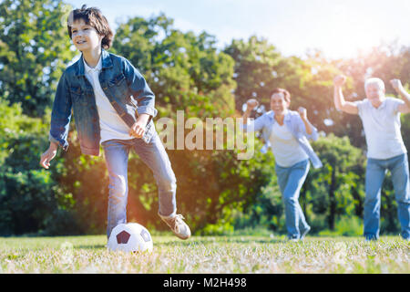 Vater und Opa Zujubeln für Enkel spielen Fußball Stockfoto