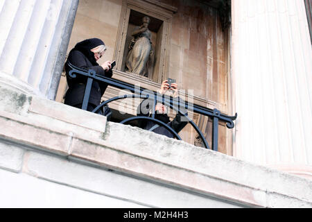 Zwei Leute mit ihren Handys außerhalb der National Gallery in London. Stockfoto