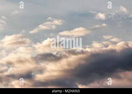 Schöne bewölkter Himmel bei Sonnenuntergang. Abstrakte Wolkenformationen farbig in Gold durch Sonnenlicht von unten. schöne Natur Hintergrund Stockfoto