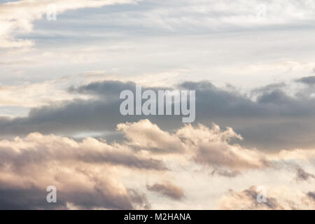 Schöne bewölkter Himmel bei Sonnenuntergang. Abstrakte Wolkenformationen farbig in Gold durch Sonnenlicht von unten. schöne Natur Hintergrund Stockfoto