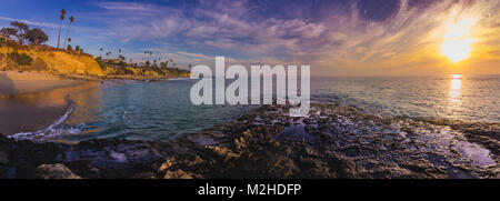 Panorama Ansicht eines farbenfrohen Himmel nach Sonnenuntergang mit Wellen und Wasser aus Tide Pools der Himmel widerspiegelt, Diver's Cove, Laguna Beach, CA Stockfoto