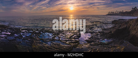 Panorama Ansicht eines farbenfrohen Himmel nach Sonnenuntergang mit Wellen und Wasser aus Tide Pools der Himmel widerspiegelt, Diver's Cove, Laguna Beach, CA Stockfoto