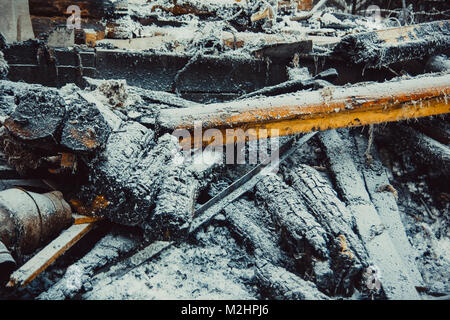Verkohlte Glut, bedeckt mit Raureif liegen auf dem Schnee Stockfoto
