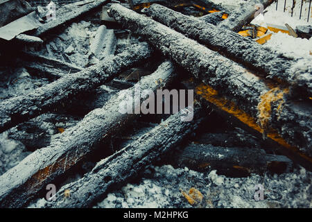 Verkohlte Glut, bedeckt mit Raureif liegen auf dem Schnee Stockfoto