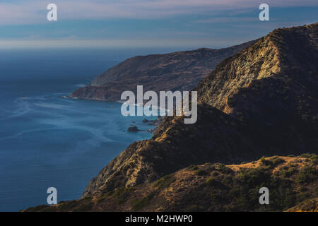 Atemberaubende Berggipfel Blick auf robuste Catalina Küstenlinie und Schluchten an einem sonnigen Tag mit Wolken im Himmel und schönen blauen Wasser, Catalina Island, Kalifornien Stockfoto