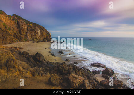 Der abgeschiedenen Pirate Cove Strand bei Sonnenuntergang mit einem bunten Himmel und Meer Wasser fließt, um Felsformationen, Point Dume, Malibu, Kalifornien Stockfoto