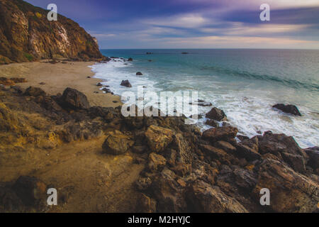 Der abgeschiedenen Pirate Cove Strand bei Sonnenuntergang mit einem bunten Himmel und Meer Wasser fließt, um Felsformationen, Point Dume, Malibu, Kalifornien Stockfoto