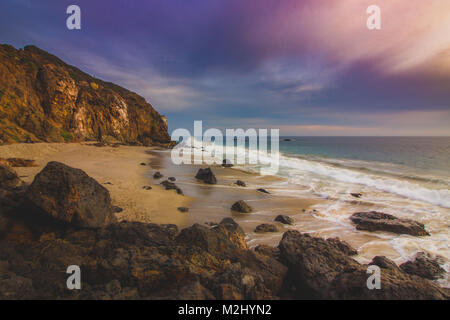 Der abgeschiedenen Pirate Cove Strand bei Sonnenuntergang mit einem bunten Himmel und Meer Wasser fließt, um Felsformationen, Point Dume, Malibu, Kalifornien Stockfoto