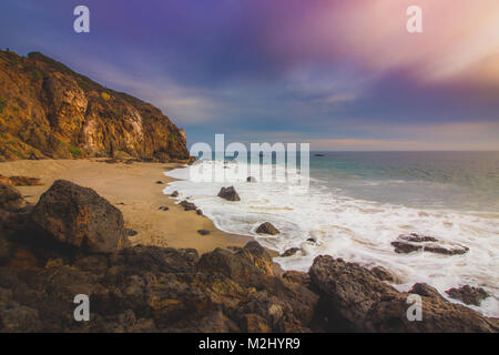 Der abgeschiedenen Pirate Cove Strand bei Sonnenuntergang mit einem bunten Himmel und Meer Wasser fließt, um Felsformationen, Point Dume, Malibu, Kalifornien Stockfoto