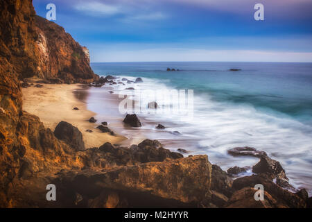 Der abgeschiedenen Pirate Cove Strand bei Sonnenuntergang mit einem bunten Himmel und Meer Wasser fließt, um Felsformationen, Point Dume, Malibu, Kalifornien Stockfoto