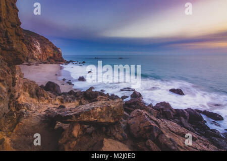 Der abgeschiedenen Pirate Cove Strand bei Sonnenuntergang mit einem bunten Himmel und Meer Wasser fließt, um Felsformationen, Point Dume, Malibu, Kalifornien Stockfoto