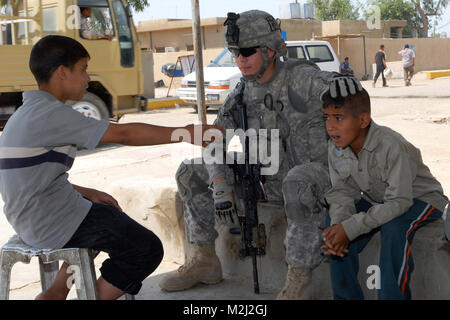 100506-A-6124 H-035 HAMAMIAT, Irak-Pfc. Daniel Flores, ein rifleman mit Firma B, 2.Bataillon, 23 Infanterie Regiment, 4 Stryker Brigade Combat Team, 2 Infanterie Division, Anleihen mit lokalen Kinder außerhalb einer falafel Shop hier, 6. Mai, während ein noncommissioned Officer von seinem platoon Micro grant Unterlagen an die Eigentümer gibt. Eine micro Grant stellt Geld durch den Kommandanten "Emergency Response Program, um Elemente wie Generatoren Geschäft im Bereich zu fördern. (U.S. Armee Foto von Pfc. Kimberly Hackbarth, 4 SBCT PAO, 2. Inf. Div.) Treffen einige der Einheimischen, die von den 1st Armored Div. Stockfoto