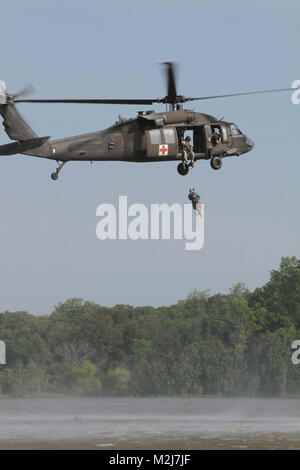 Eine der Oklahoma Army National Guard UH-60 Black Hawk schwebt über See Thunderbird als Soldat als mock Opfer wird aus dem Wasser während über dem Wasser hoist Training, 6. Juni gehisst. (U.S. Armee Foto von SPC. Jared Sollars, 145 Mobile Public Affairs Loslösung) 06052010-A -5482 S-482 durch Oklahoma National Guard Stockfoto