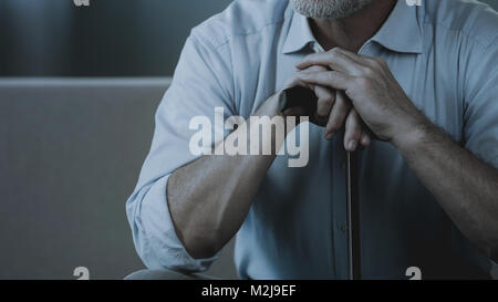 Nahaufnahme der erwachsenen männlichen Händen hält Spazierstock, alte Mann sitzt auf einem Sofa, Filmmaterial Stockfoto