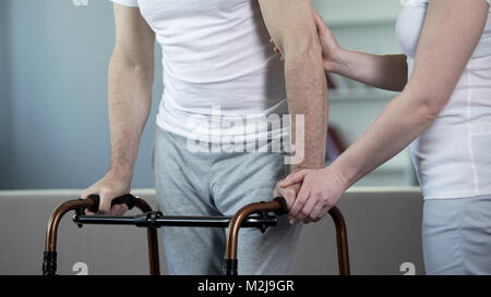 Frau helfen kranken älteren Mann mit Gehhilfe, Rehabilitation, Filmmaterial Stockfoto