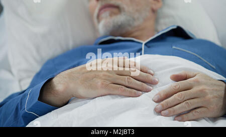 Blick auf überlasteten faltigen Hände der weise, alte Mann friedlich schlummernden im Bett, Filmmaterial Stockfoto