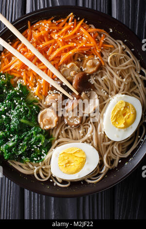 Soba Nudeln Suppe mit Gemüse, Shiitake-Pilze, Ei und Sesam close-up in eine Schüssel geben. Vertikal oben Ansicht von oben Stockfoto