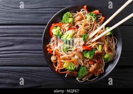 Gebratenen Soba Nudeln mit Champignons, Brokkoli, Möhren, Paprika closeup auf einem Teller auf dem Tisch. horizontal oben Ansicht von oben Stockfoto